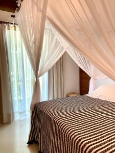 a bedroom with a bed with a canopy and windows at CASA PREGUIÇA - TRANCOSO - ECO in Trancoso