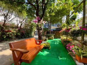 a wooden bench sitting in a garden with flowers at Chedi Chiangrai Boutique Hotel in Chiang Rai