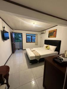Un dormitorio con una cama, un escritorio y un televisor. en Omah Kenangan at Seven Trumpets Resort, en Seturan