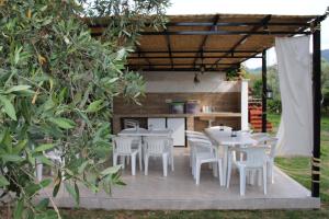 a patio with white tables and chairs and a kitchen at Patroudis House in Skala Rachoniou