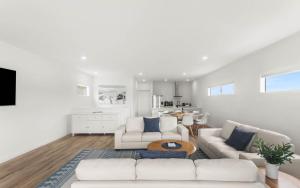 a living room with two white couches and a table at Modern Beachhouse, sea views in McCracken