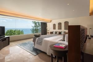 a bedroom with a large bed and a large window at Anantara Uluwatu Bali Resort in Uluwatu