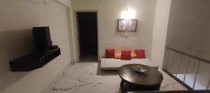 Una pequeña sala de estar con un sofá y un televisor. en Bougainville Rooms, en Sāhāpur