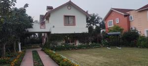 una casa blanca con un patio con flores en Bougainville Rooms, en Sāhāpur
