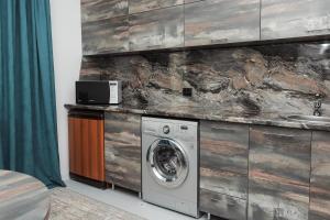 a washer and dryer in a room with a stone wall at Люкс Крупская 78 in Pavlodar +6 photos
