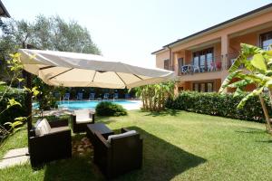 patio z parasolem i krzesłami oraz basenem w obiekcie Residence Villa Andrea w mieście Marina di Camerota