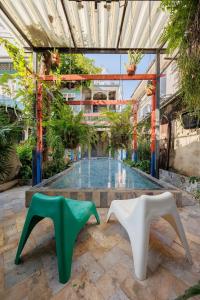 einen Innenhof mit zwei weißen und grünen Stühlen vor einem Pool in der Unterkunft The Anonymous House in Bangkok
