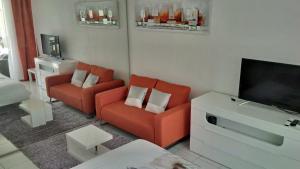 un soggiorno con 2 sedie arancioni e una TV di Joli Studio Vue Sur Mer a Pointe-à-Pitre