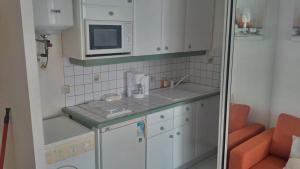 a small kitchen with white cabinets and a microwave at Joli Studio Vue Sur Mer in Pointe-à-Pitre