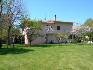 Une grande maison blanche avec des arbres dans la cour dans l'établissement Hotel Ristorante Vecchia Maremma, à Orbetello