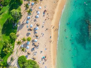 een uitzicht over een strand met mensen en parasols bij Ocean Villas at Turtle Bay in Kahuku