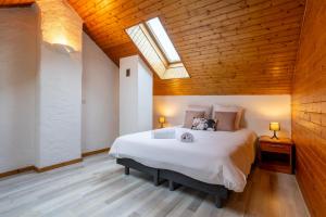 Un dormitorio con una gran cama blanca con tragaluz. en Le Refuge proche de Genève, en Viry