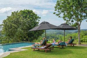 a group of people sitting in chairs under umbrellas by a pool at Heavensa Luxury Villas and Suites by The Clarks in Galle