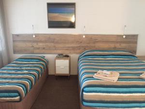 Zimmer mit 2 Betten und einem TV an der Wand in der Unterkunft A & A Motel in Proserpine