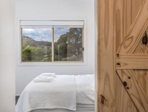 a bedroom with a white bed and a window at THE SHED - Tallebudgera Valley in Tallebudgera