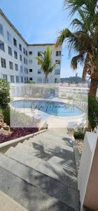 a swimming pool in front of a building with palm trees at Casa Memmar in Acapulco
