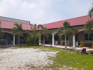 a building with a table and chairs and palm trees at Four F Motel by Lily in Pantai Cenang