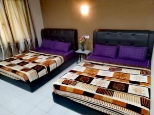 two beds sitting next to each other in a room at Four F Motel by Lily in Pantai Cenang
