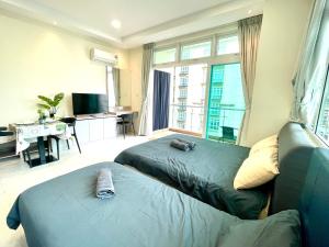 a hotel room with two beds and a desk and a window at Kuching City Center Riverine Apartment With Balcony and Garden View in Kuching