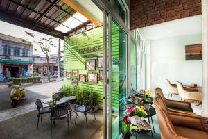 a green building with a table and chairs on a street at 217@HKT in Phuket