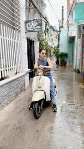 een vrouw zit op een scooter op straat bij Uni Homestay 2 in Hai Phong