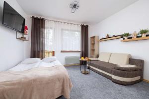 un dormitorio con una cama y un sofá en Bright Studio with Balcony in Murzasichle by Noclegi Renters, en Murzasichle