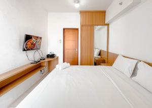 Un dormitorio con una cama blanca y un televisor. en Simple and Relax Studio at Pavilion Permata Apartment By Travelio, en Surabaya 9 fotos más