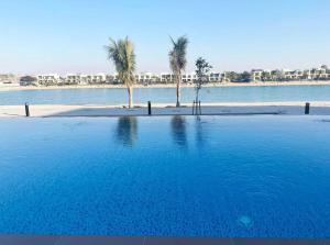 a large swimming pool with palm trees in the water at RAKvista Residence in Ras al Khaimah