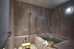 a bathroom with a tub with a shower and a stool at Hotel Royal Chihpin in Wenquan +68 photos