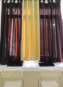 two chairs sitting in front of a window with curtains at Casa Bahia Dive Resort in Bagalañgit