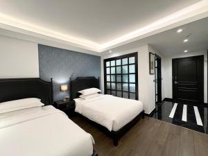une chambre avec deux lits et une fenêtre dans l'établissement Glory Boutique Suites 清迈古城荣耀精品酒店, à Chiang Mai