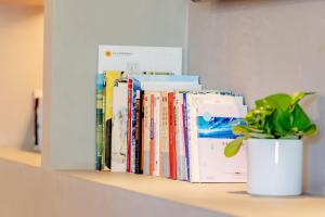 una pila di libri su uno scaffale con una pianta in vaso di 北京方庄万信至格酒店 a Pechino