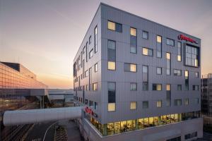 un edificio alto gris con una puesta de sol en el fondo en Hampton by Hilton London Gatwick Airport, en Horley