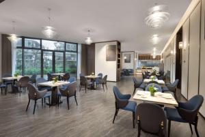 a restaurant with tables and chairs and windows at Hawthorn by Wyndham Jinghong Mengyang in Pan-na-meng-yang