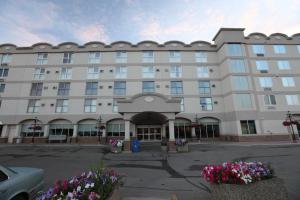 um grande edifício branco com flores num parque de estacionamento em St. Albert Inn & Suites em St. Albert