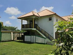 une petite maison blanche avec un escalier dans une cour dans l'établissement Jackson Breezy Vacation and Venue Rental Barbados, à Saint Michael