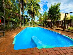 a blue swimming pool with palm trees in the background at Tropical River Hotel in Katherine