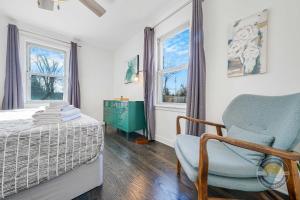 a bedroom with a bed and a chair and two windows at NEW Urban Comfort On Grant St in Lake Geneva