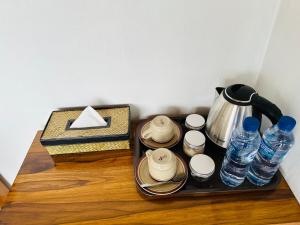 a tray with cups and water bottles on a table at Pinggan Campside Glamping in Baturaja