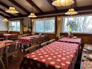 a restaurant with tables and chairs with red table cloth at ハノイペンション in Higashi-gumi