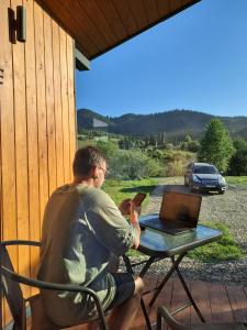 a man sitting at a table with a laptop at Family House Volosianka in Volosyanka
