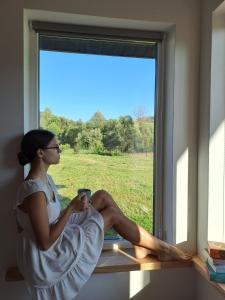 a woman sitting on a window sill holding a cell phone at Family House Volosianka in Volosyanka