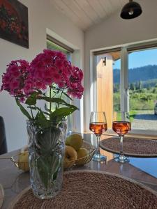 a vase with pink flowers on a table with two glasses at Family House Volosianka in Volosyanka