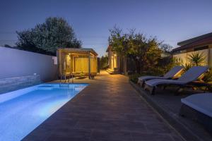 AsgourouにあるCity Art Villaの椅子2脚と家のあるプール