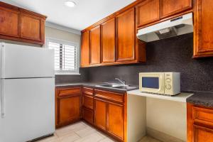 a kitchen with wooden cabinets and a white refrigerator at Americas Best Value Inn Houston Heights at I-45 in Houston