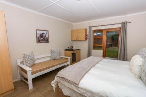 a bedroom with a bed and a bench and a window at River Bend Farm in Lidgetton