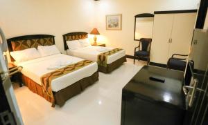 a hotel room with two beds and a television at Ongville Hotel & Events Place in Candelaria