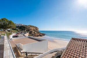 a beach with a building and the ocean at Beach Apt 1 In Burgau in Burgau