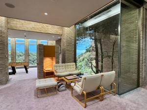 a living room with chairs and a large window at 熱海山荘 in Atami