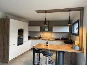 a kitchen with white cabinets and a wooden counter top at Superbe villa avec piscine proche de belfort in Meroux